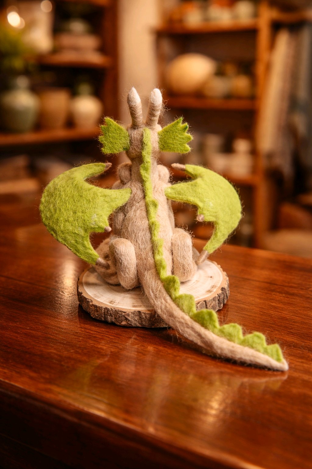 großer Filzdrache auf Holzscheibe