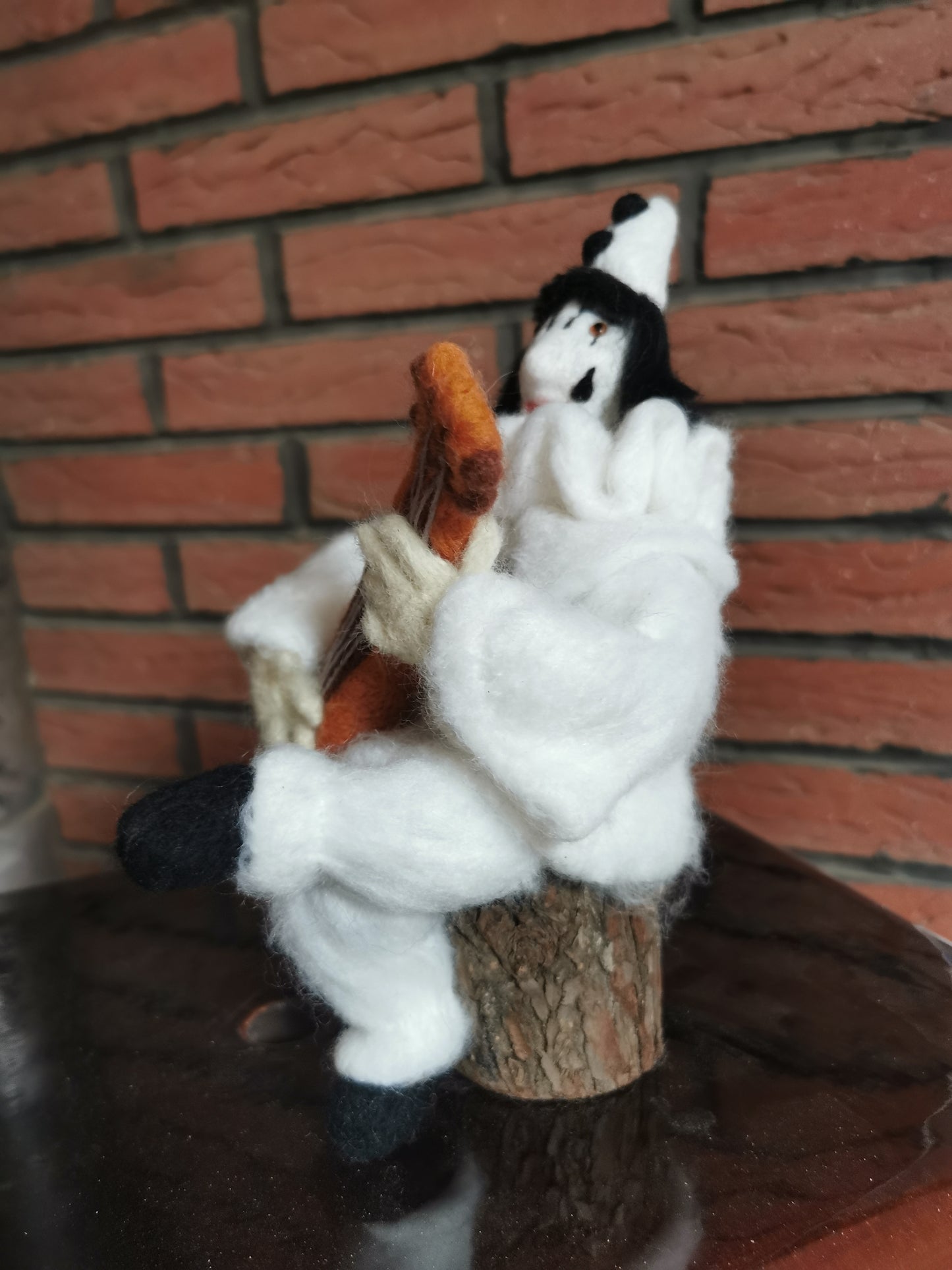 Pierrot Clown mit Gitarre auf Holzstamm
